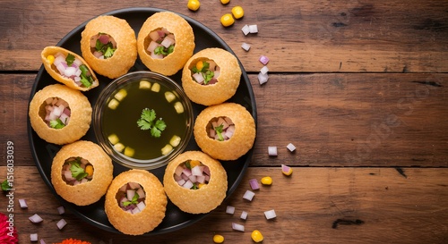 several pani puris arranged in a circular pattern at the top right third, with a small bowl of flavored water in the center.