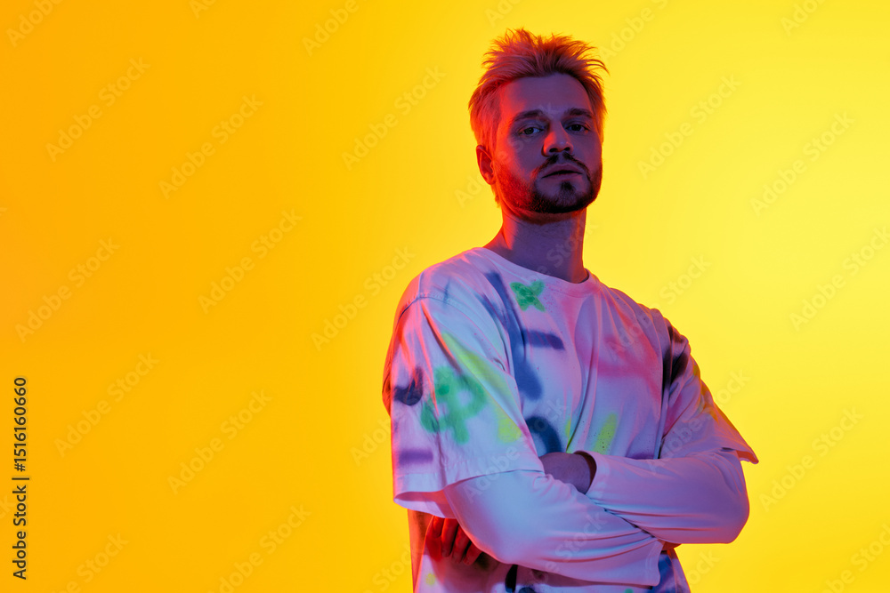 Handsome young man stands confidently in front of a vibrant yellow backdrop Handsome young man stands confidently in front of a vibrant yellow backdrop