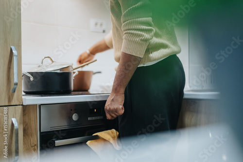 Fotografi Image of a person preparing a meal in a modern kitchen, demonstrating the activity of cooking and food preparation with pots and household appliances