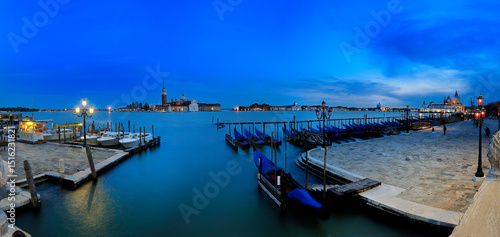 Gondolas resting in venice at blue hour with san giorgio maggiore church