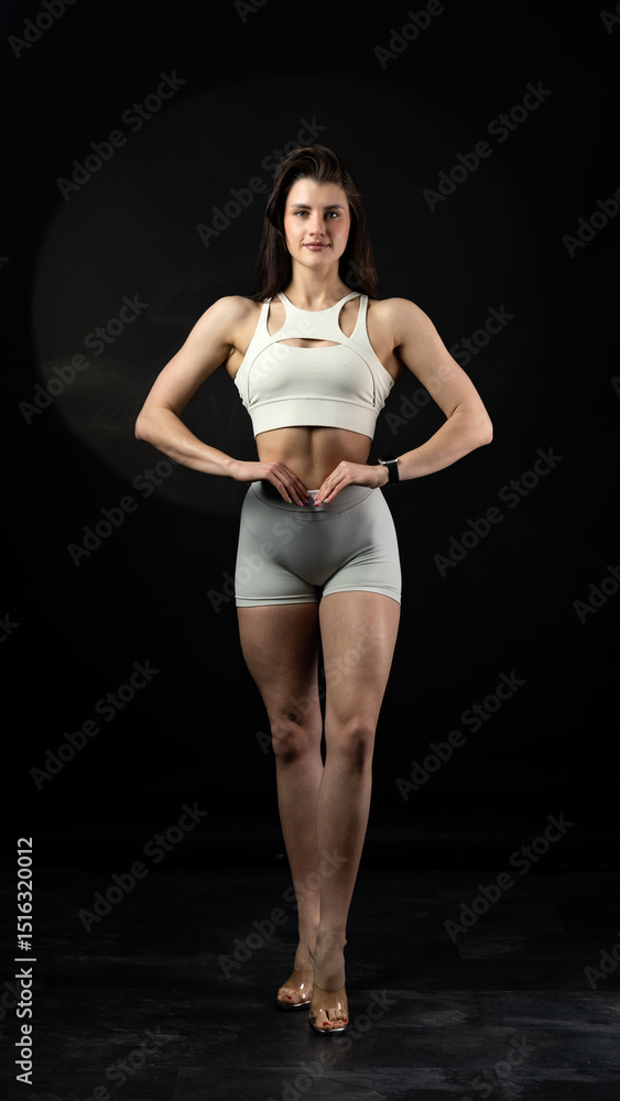 Fototapeta premium Athletic woman standing on black background, showing her fit body