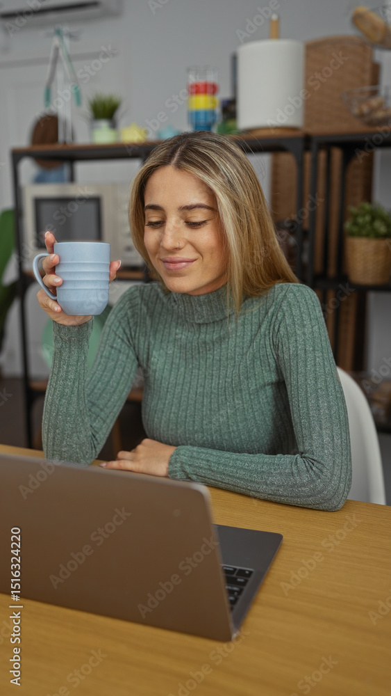 Fototapeta premium Woman smiling while holding a coffee mug at a desk in an office environment, working on a laptop, showcasing a casual and professional atmosphere indoors.