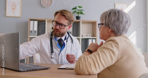 Experienced male doctor explaining lab tests results to senior woman who came on medical appointment, giving prescription and recommendations. Old patient being on check up in clinic