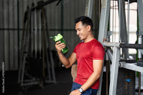 Fitness Hydration. Young man enjoying a sports drink in gym. photo