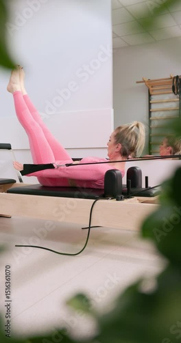Vertical video of mature woman on pilates reformer machine