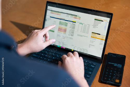 A person is using a calculator and laptop at the same time