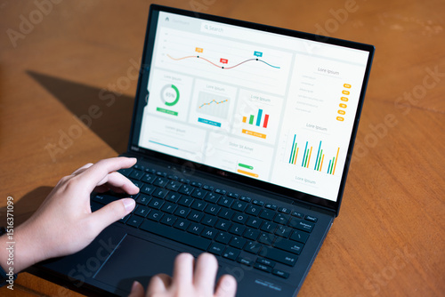 A person is typing on a laptop with a graph on the screen