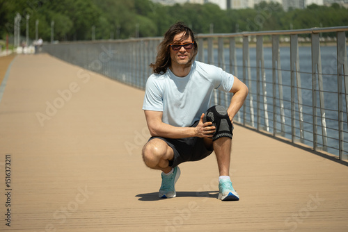 Man wearing knee brace to support painful leg. Athlete bodybuilder leg wearing knee support brace or elastic kneecap bandage. Health problems and pain. Sudden pain in knee