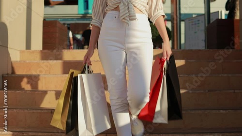 Stylish female navigating staircase, holding colorful shopping bags, expressing confident retail enthusiasm with bright smile and energetic movement.Consumerism, sale, purchase, shopping, shopping,