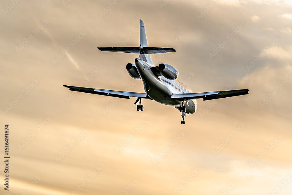 Fototapeta premium Private business jet flying under an orange sunset sky