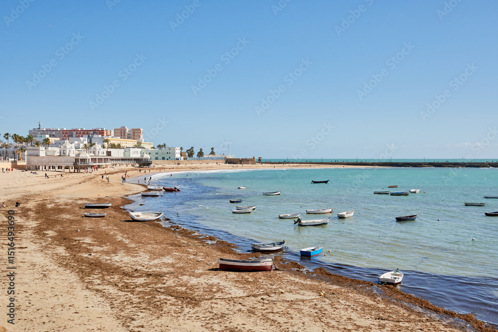 Fishing boats on La Caleta beach in Cádiz, Spain, under a clear blue sky Fishing boats on La Caleta beach in Cádiz, Spain, under a clear blue sky