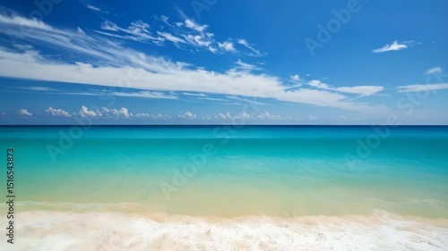 Vivid ocean scene with turquoise water, white sand beach, rolling waves, and a blue sky with wispy clouds during daytime.