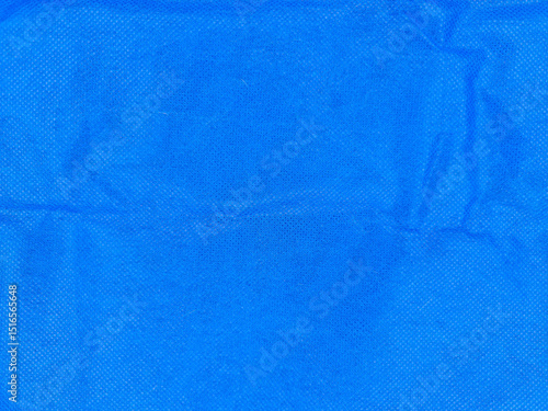 фотографія Bright blue textured fabric with subtle wrinkles and a grainy surface pattern, showcasing variations in shading and light