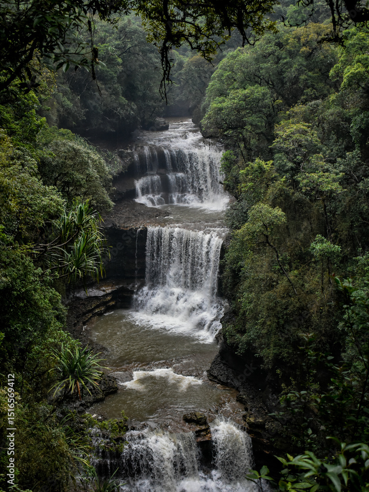 Obraz premium Wei sawdong , a multitiered waterfall cascading down rocky cliffs, surrounded by lush green foliage. A beautiful waterfall in Meghalaya.
