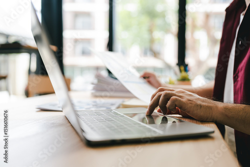 Portrait of a man working with documents using laptop in modern office. Preparing accounting analysis report, real estate investment information, finance and tax concept.