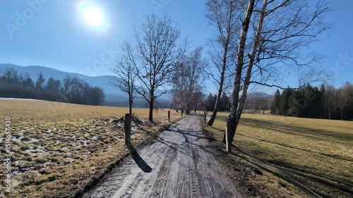 A walk down the dirt road through a muddy rural area on a sunny day