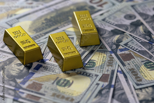 Three gold bars rest on spread of hundred dollar bills, symbolizing wealth and investment. shiny gold contrasts with detailed currency, creating luxurious and financial theme