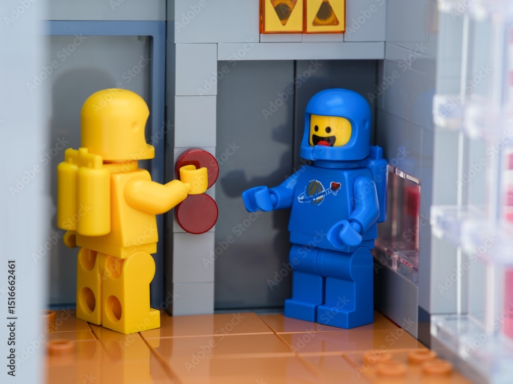 Obraz premium Tambov, Russian Federation - May 26, 2025 Two Lego astronaut minifigures waiting at an elevator. The yellow one is pressing a button on the elevator.