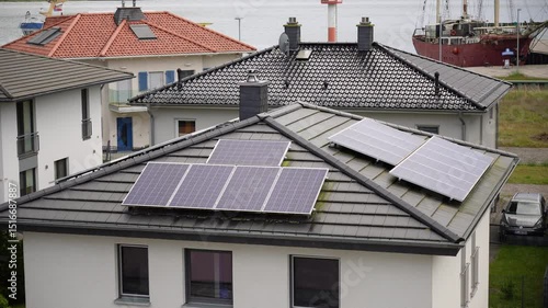 Rooftop solar panels provide clean energy atop modern houses near the water and a docked ship showing sustainable development for eco friendly buildings and renewable power