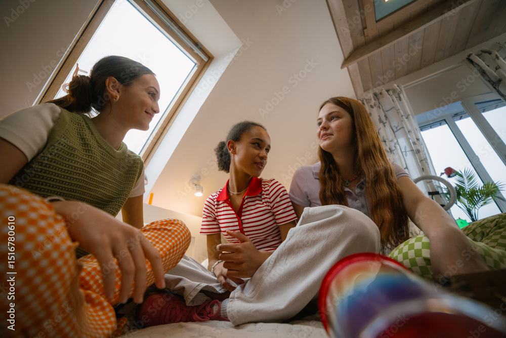 Obraz premium Three teenage girls spend time together. They chat in the bedroom.