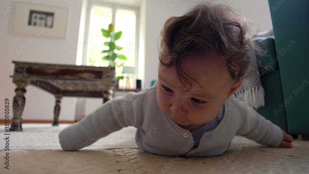 Naklejka premium Baby lying on the floor, pushing up with both arms, looking forward with curiosity, exploring surroundings in a cozy home setting, early stages of learning to crawl