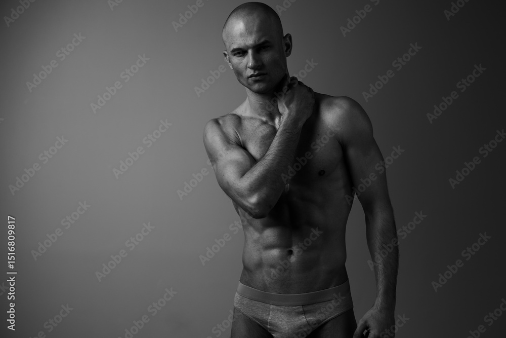 Fototapeta premium Black and white portrait of a muscular man expressing confidence and strength, showcasing his well-defined physique and powerful presence.