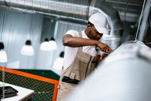 Obraz na plátně Worker performs maintenance on ventilation system in modern industrial space dur