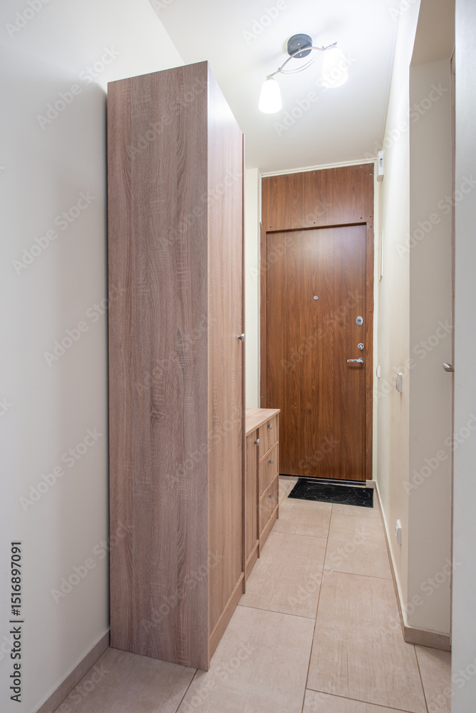 Fototapeta premium Narrow Entryway with Wooden Cabinet and a Closed Door View