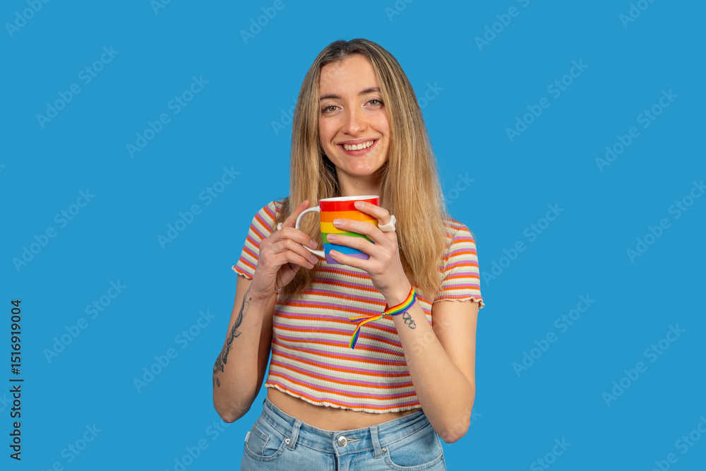 Smiling young woman holding rainbow mug and wearing rainbow bracelet: celebrating pride month with coffee Smiling young woman holding rainbow mug and wearing rainbow bracelet: celebrating pride month with coffee