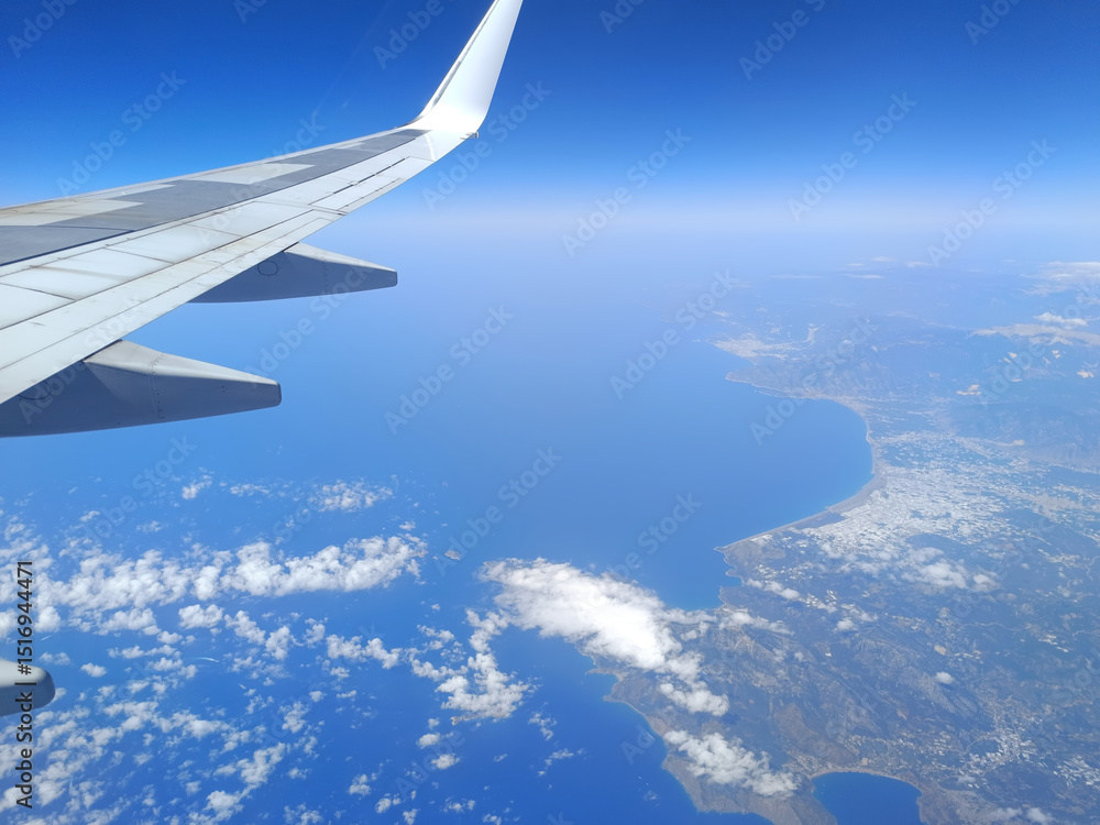 Obraz premium Aerial view from airplane window over the Mediterranean coast with wing in frame
