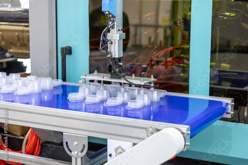 Production line for the production of plastic packaging by injection molding. Small round disposable containers on a conveyor, automation and modern production technologies