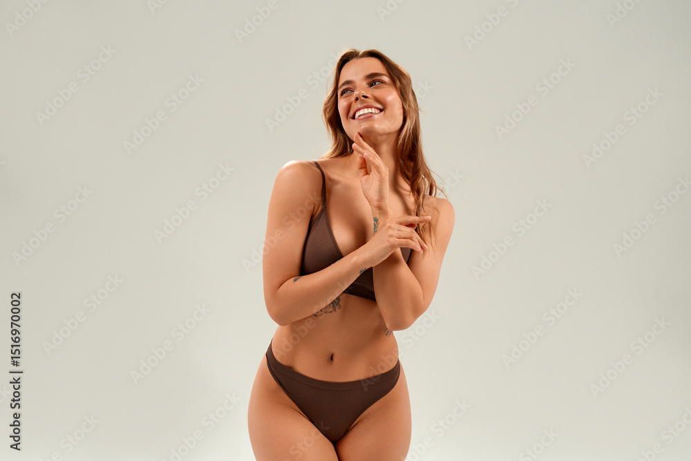 Fototapeta premium Smiling woman in brown underwear posing confidently on white background