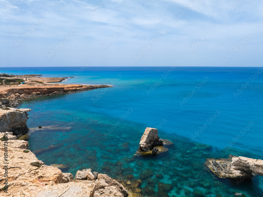 Ayia Napa coastline in Cyprus with turquoise waters, rugged rocky formations, sandy and rocky terrain, and a clear blue sky in the background. Ayia Napa coastline in Cyprus with turquoise waters, rugged rocky formations, sandy and rocky terrain, and a clear blue sky in the background.