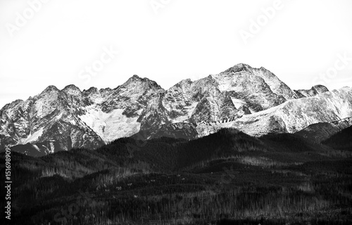 Fototapeta Naklejka Na Ścianę i Meble -  Czarno-biały panoramiczny widok na Tatry z miejscowości Zdziar na Słowacji. Surowy krajobraz górski z dramatycznym niebem i wyraźnym rysunkiem grani tworzy nostalgiczny, nastrojowy klimat.