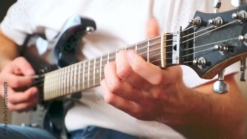 Man playing guitar at home, pinching strings with fingers, playing chords, hands closeup