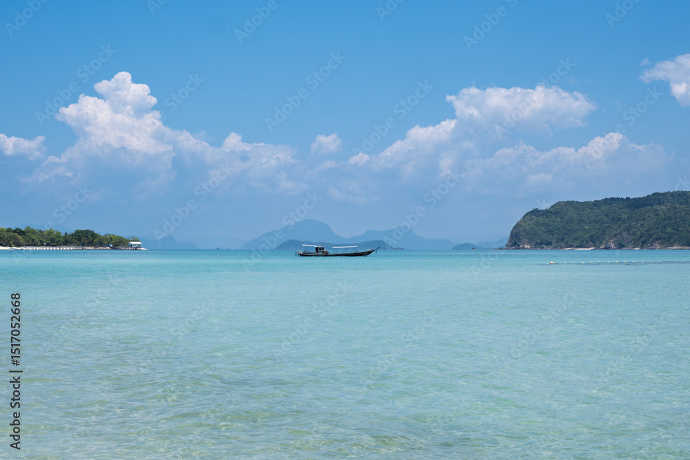 Fototapeta premium Landscape photo of a Thai longtail boat from the paradise island of Pig Island (Koh Madsum) in Koh Samui. Beautiful tropical landscape with turquoise blue water and lush vegetation, on a beautiful sun