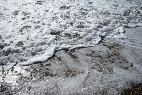 Foamy sea wave washing over a pebbly shore