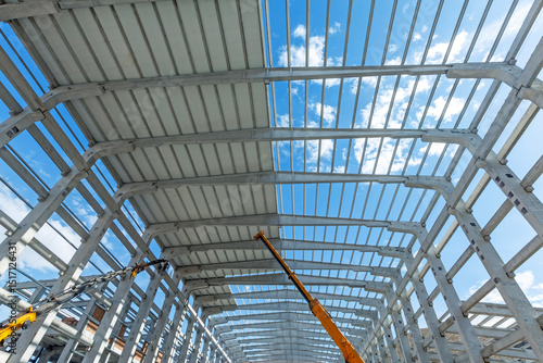 Covering is being done on precast roof. Interior view of the walls, supports, and roof of a precast commercial industrial prefabricated concrete. It is a construction product.