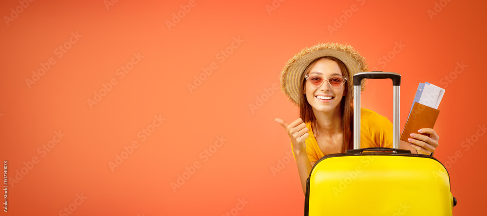Special deal for travellers. Happy young woman in sunglasses and summer hat holding passport with plane tickets, standing next to big luggage and showing thumb up, yellow background with copy space Special deal for travellers. Happy young woman in sunglasses and summer hat holding passport with plane tickets, standing next to big luggage and showing thumb up, yellow background with copy space