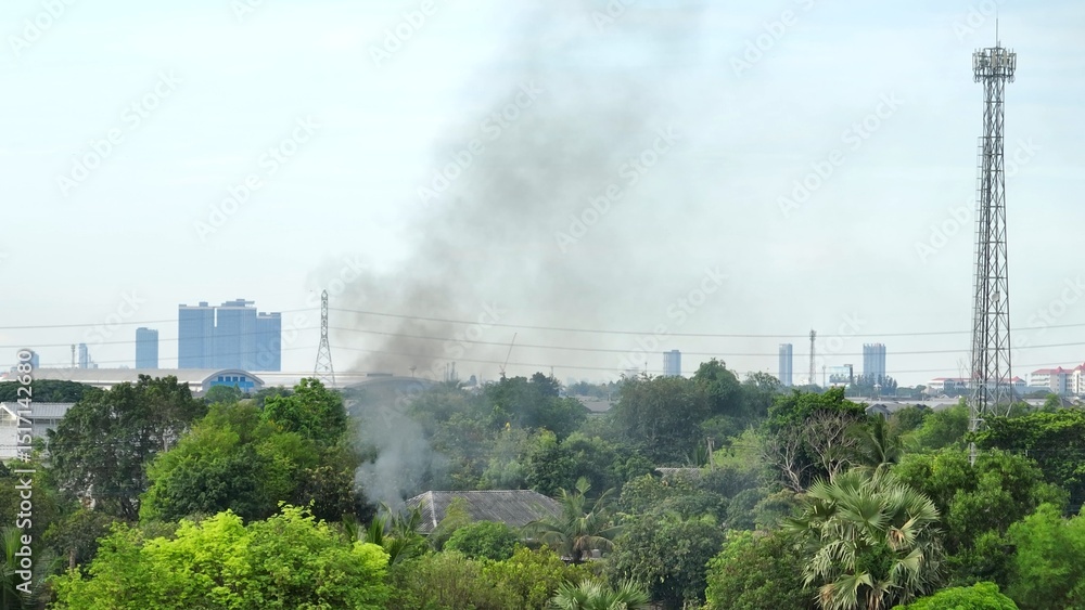 An aerial view captures the rising smoke from households, contributing to air pollution in urban settings, emphasizing the need for better waste management.
