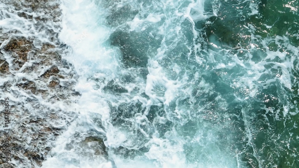 An aerial view captures the moment a wave crashes, sending a burst of water upwards, highlighting the dramatic force of the ocean as it meets the rocks.
An aerial view captures the moment a wave crashes, sending a burst of water upwards, highlighting the dramatic force of the ocean as it meets the rocks.