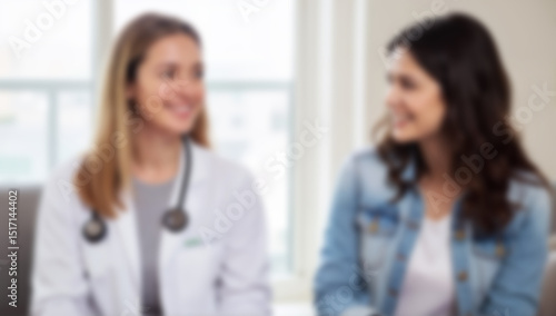 Blurred medical-professional image shows two women in a healthcare setting. Image is suitable for illustrating medical consultation or patient interaction.