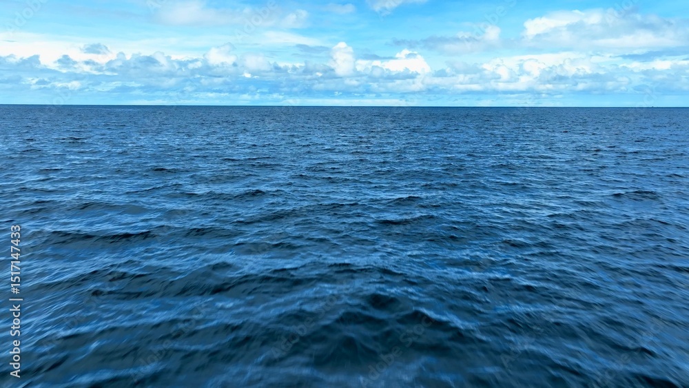 Fototapeta premium A tranquil aerial view of the vast ocean, showcasing the endless blue waters under a sky filled with soft clouds, perfect for themes of serenity, nature, and expansive landscapes. Phuket, Thailand. 
