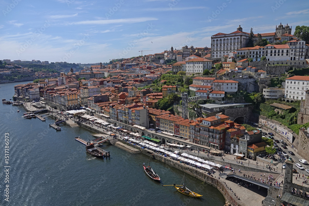Obraz premium A cityscape view of the Ribeira historical district of Porto, Portugal is shown alongside the Douro River during the day.