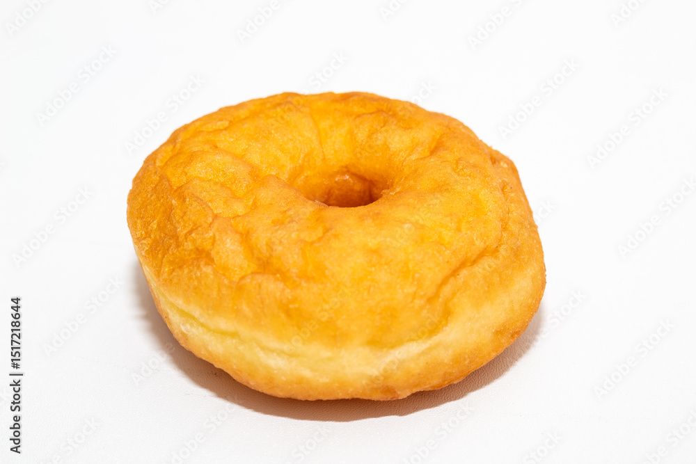 A classic, golden-brown donut with a slight rise, perfectly centered on a clean white surface. A classic, golden-brown donut with a slight rise, perfectly centered on a clean white surface.