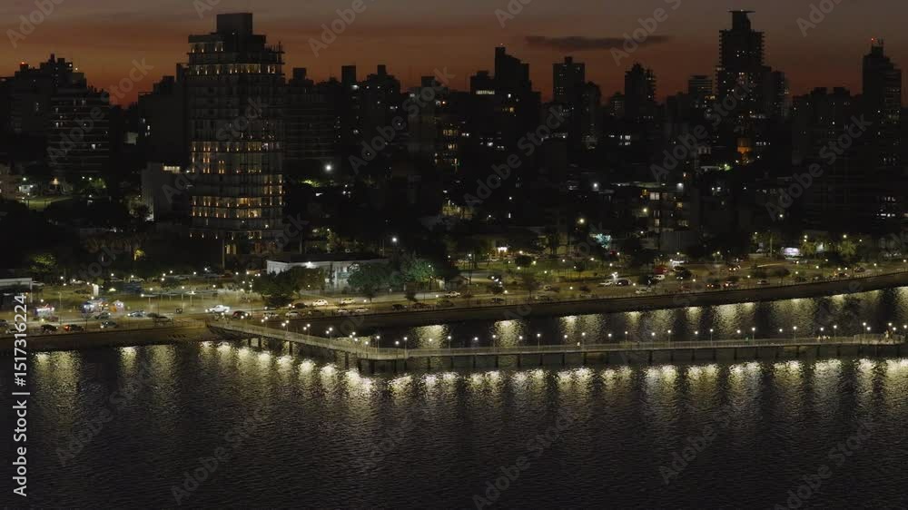 Night view of Posadas with illuminated bridge reflecting on water and vibrant city lights. Night view of Posadas with illuminated bridge reflecting on water and vibrant city lights.