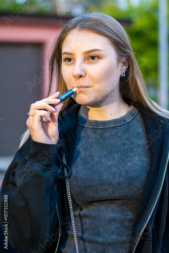 Wallpaper Mural Young woman smoking e-cigarette in the street. Addiction concept. High quality photo.	 Torontodigital.ca