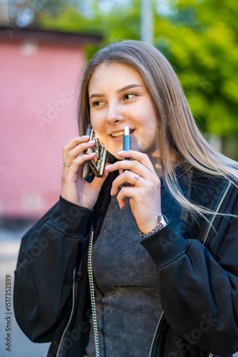 Wallpaper Mural Young woman smoking e-cigarette talking on the phone in the street. Addiction concept. High quality photo.	 Torontodigital.ca