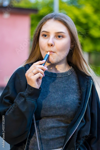 Wallpaper Mural Young woman smoking e-cigarette in the street. Addiction concept. High quality photo.	 Torontodigital.ca