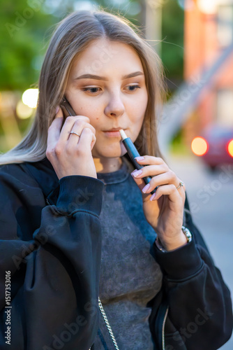 Wallpaper Mural Young woman smoking e-cigarette talking on the phone in the street. Addiction concept. High quality photo.	 Torontodigital.ca